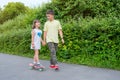 Brother and sister on a walk in the park. The boy teaches a girl to ride a skateboard, a board