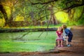 Brother and sister walking near an artificial lake under the branches of trees Royalty Free Stock Photo