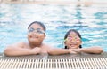 Brother and sister wear goggle and smile in swimming