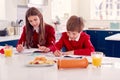 Brother And Sister Wearing School Uniform Doing Homework On Kitchen Counter With Healthy Snacks Royalty Free Stock Photo