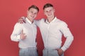 Brotherhood and friendship concept. Happy men hugging. Two brothers smiling and pointing finger. Models standing on red Royalty Free Stock Photo