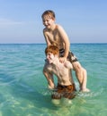 Brothers are enjoying the clear warm water in the ocean and play pickaback Royalty Free Stock Photo