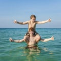 Young brothers are enjoying the clear warm water at the beautiful beach and playing pickaback Royalty Free Stock Photo