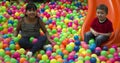 Brothers lays on the big heap of multicolored small balls.