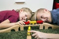 Brothers play with wooden train, build toy railroad at home or d Royalty Free Stock Photo