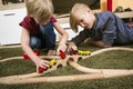 Brothers play with wooden train, build toy railroad at home or d Royalty Free Stock Photo