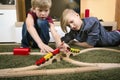 Brothers play with wooden train, build toy railroad at home or d Royalty Free Stock Photo