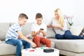 Brothers playing card game on living room sofa at home supevised by their mother. Royalty Free Stock Photo