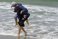 Brothers playing piggyback at the edge of waves on coast