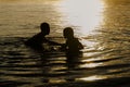 Brothers playing in the water of a lake at sunset Royalty Free Stock Photo