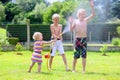 Brothers and sister playing with water hose in the garden Royalty Free Stock Photo