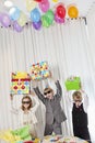 Brothers and sister wearing sunglasses holding gift aloft while shouting Royalty Free Stock Photo