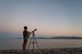 Brothers standing on beautiful pebble beach looking to the stars with a telescope Royalty Free Stock Photo