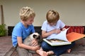 Brothers and their cat looking a book Royalty Free Stock Photo