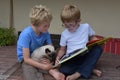 Brothers and their cat looking a book Royalty Free Stock Photo