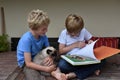 Brothers and their cat looking a book Royalty Free Stock Photo