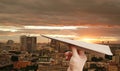 Brown aircraft rocket paper in hand fold on the city background at sunset