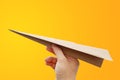 Brown aircraft rocket paper in hand fold to success isolated on yellow-orange background, Concept for business and travel plant