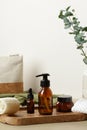 Brown amber glass cosmetic bottles on wooden tray on table with cosmetic bag and eucalyptus. Luxury SPA bathroom beauty products Royalty Free Stock Photo