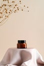 Brown amber glass jar of natural moisturizing face cream on podium with dry flowers on beige background Royalty Free Stock Photo