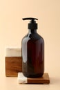 Brown amber glass shampoo bottle on stone and wood pedestal. Beauty product branding, display