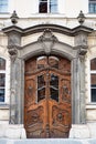 Brown antique wooden door with figures of heads and glass inserts in a baroque arch with stucco in an old house on a European Royalty Free Stock Photo