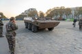 Brown armored military vehicle in procession near the entrance to the main building for the disabled in Paris.