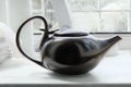 Brown asian teapot on the white windowsill