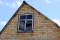 Brown attic of a brick house with a broken window