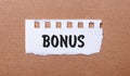 On a brown background, white paper with the inscription BONUS Royalty Free Stock Photo