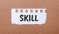 On a brown background, white paper with the inscription SKILL Royalty Free Stock Photo