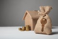 Brown bag with key logo. Gold coins and home paper house. The concept of renting and buying house Royalty Free Stock Photo