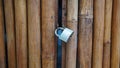 Brown bamboo door or fence, with locked gray padlock Royalty Free Stock Photo