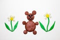 Brown bear among the flowers are made of plasticine. The bear is a forest animal.