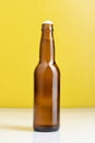 Brown beer bottle standing on a white table against a yellow background Royalty Free Stock Photo