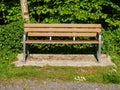 Brown bench in a park on a hot summer day. Metal frame and strong long lasting plastic materials. Park design. Sitting area