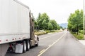 Brown big rig long haul semi truck transporting commercial cargo in semi trailer running on the divided road Royalty Free Stock Photo