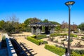 A brown and black pergola in the garden surrounded by a dirt path and lush green trees and plants Royalty Free Stock Photo