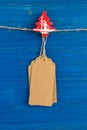 Brown blank paper price tags or labels set and Christmas wooden decoration hanging on a rope on the blue background. Royalty Free Stock Photo