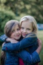 Brown and blond haired cute little girls friends smiling and hug.