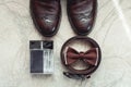 Brown bow tie, perfume, leather shoes and belt. Grooms wedding morning. Close up of modern man accessories