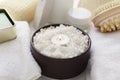 Brown bowl full of sea salt for bath procedures, candle flame, towels and other accessories for relaxation Royalty Free Stock Photo