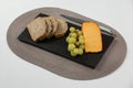 Brown bread, grapes and gouda cheese with knife on slate board Royalty Free Stock Photo