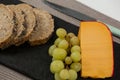 Brown bread, grapes and gouda cheese on slate board Royalty Free Stock Photo