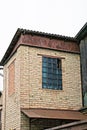 brown brick attic of a private house with a window with broken blue glass Royalty Free Stock Photo