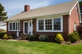 brown brick cape cod house with white window frames Royalty Free Stock Photo