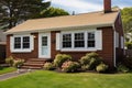 brown brick cape cod house with white window frames Royalty Free Stock Photo