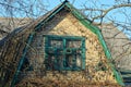 Brown brick loft of a rural house with a green window on a background of gray branches Royalty Free Stock Photo