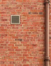 Brown Brick Wall with Vent and Old Pipe Royalty Free Stock Photo