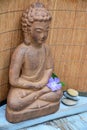 Brown Buddha statue with flowers and zen stones